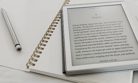 An e-reader and a writing pad on a table
