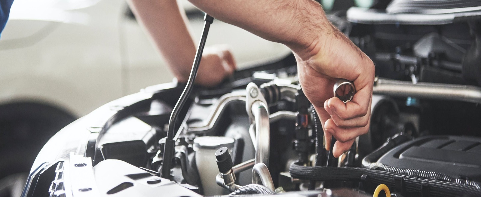 person using a tool on a car engine