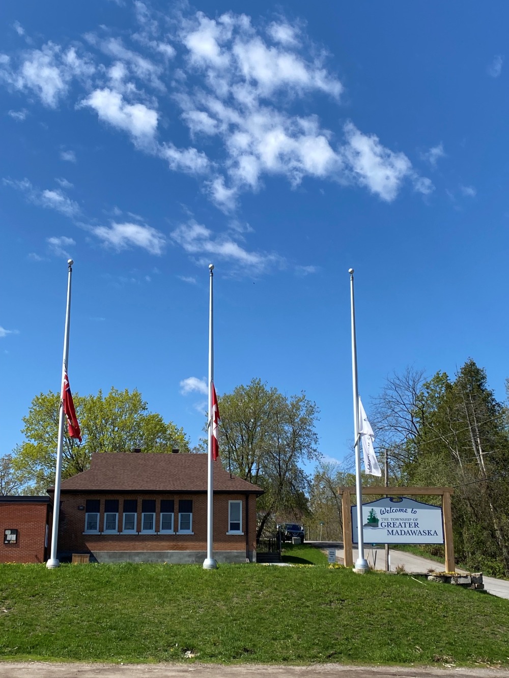 blue sky, office building, three flags at half mast
