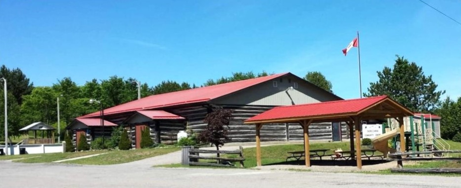 daca centre log building red roof blue sky canada flag