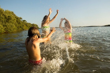 three kids swimming in lake