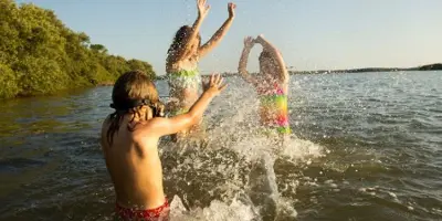 three kids swimming in lake